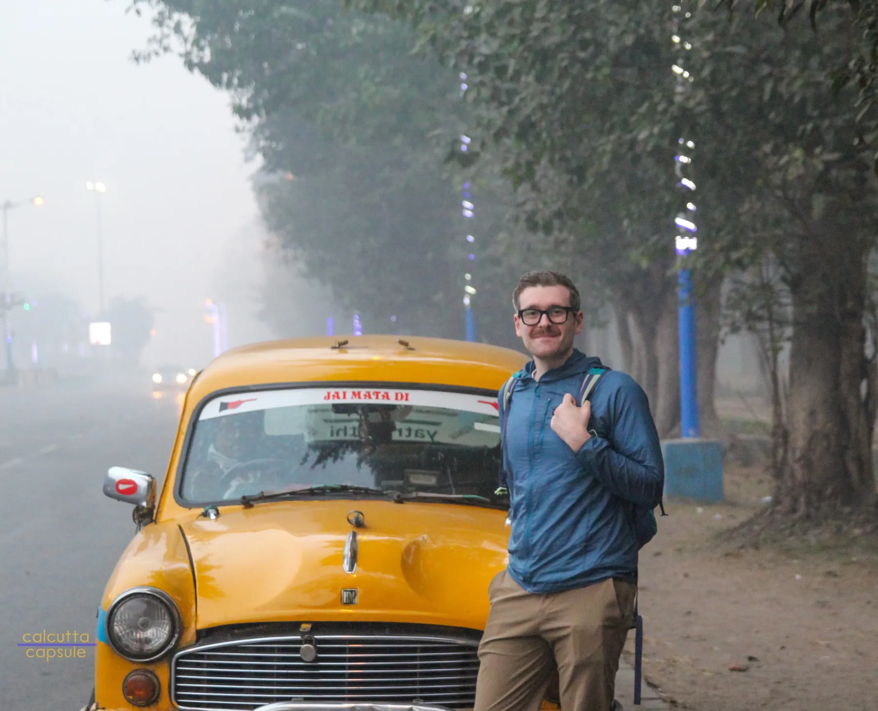 Posing with a yellow Ambassador taxi in the January fog, Kolkata