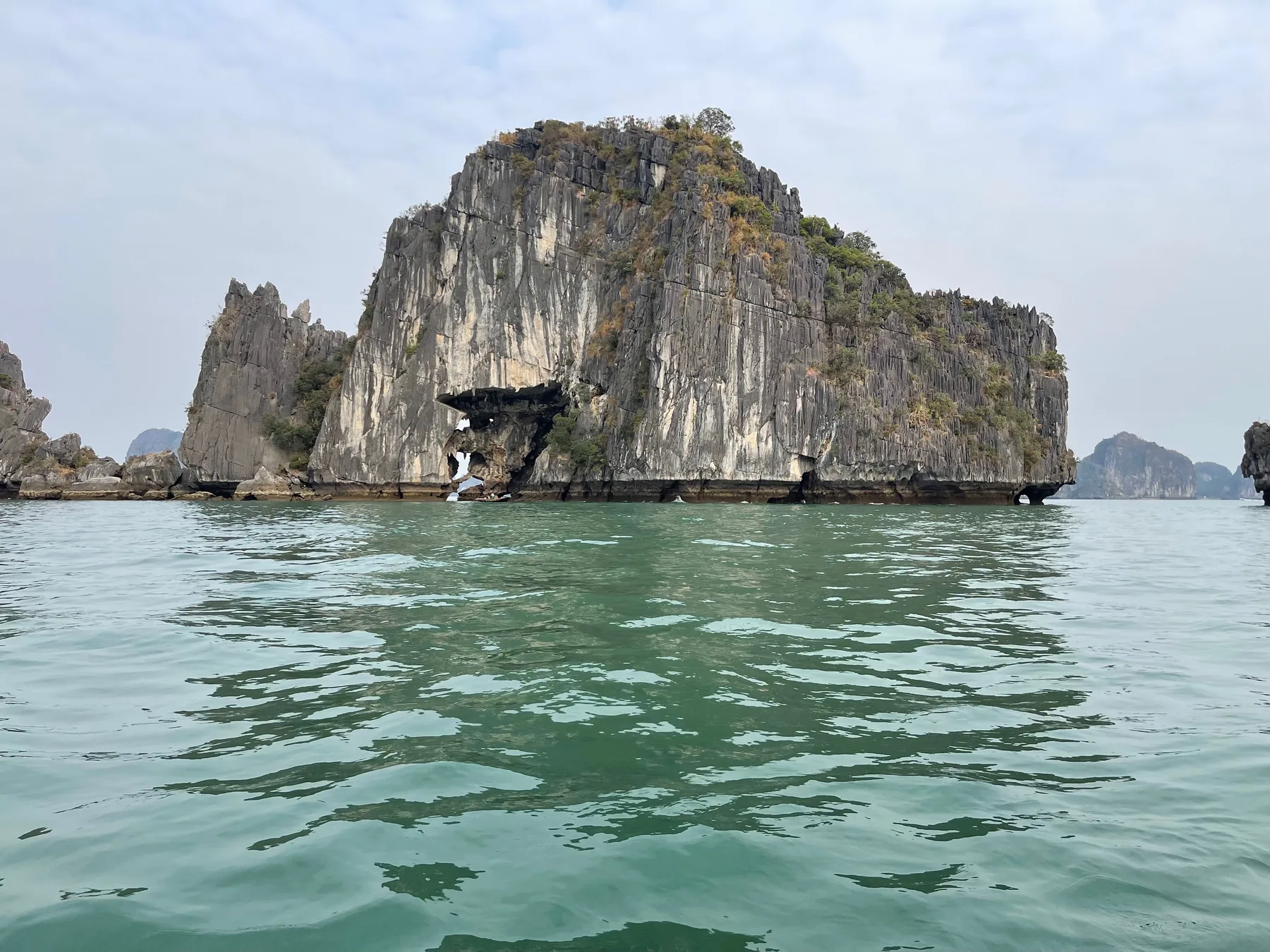 A limestone karst rising out of the green water of Ha Long Bay
