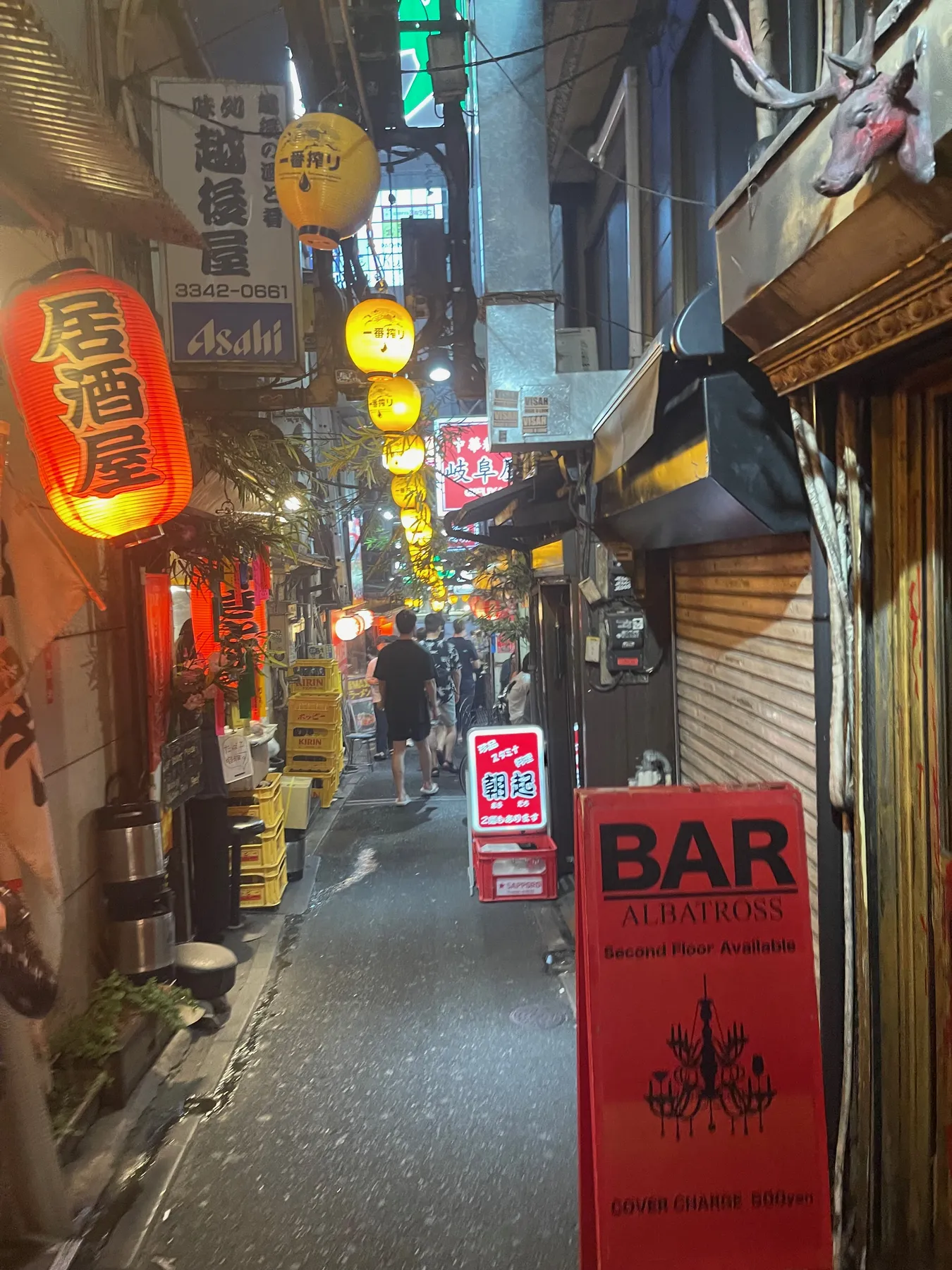 A narrow izakaya alley in Shinjuku at night, strung with glowing paper lanterns