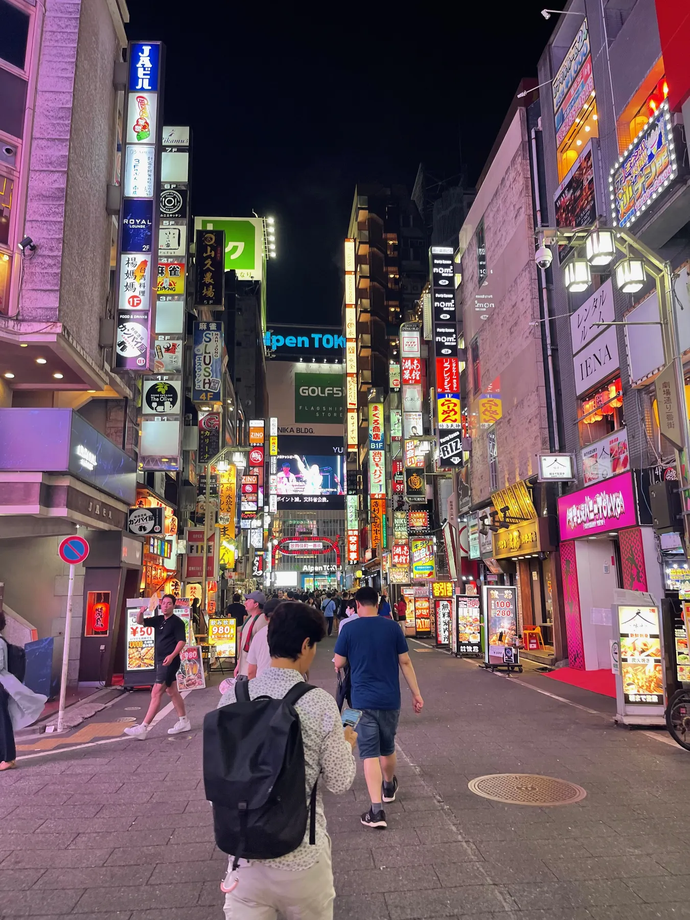 Neon signs stacked up the buildings of a Kabukicho street at night